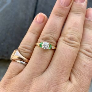 Diamond solitaire with emerald accents