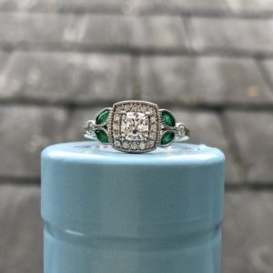 Cushion cut diamond with diamond halo and emerald accents