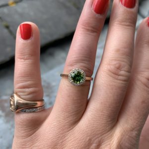 Round brilliant cut green tourmaline with diamond halo in 18ct yellow gold